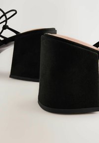 Mustad sametplatformiga sandaalid paksu kontsaga, avatud varba ja keeruka nööri disainiga. Sile sisetald mati pinnaga.
