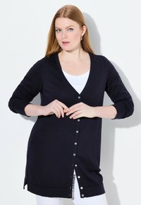 Mörk marinblå cardigan, v-ringad design, långa ärmar, knäppning fram, ribbade manschetter och nederkant, mjukt stickat material.