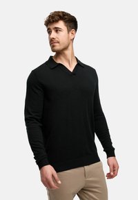 Schwarzer Strickpullover mit V-Ausschnitt und langen Ärmeln. Verfügt über gerippte Bündchen und Saum, strukturierten Stoff und ein dezentes Logo auf der Brust.