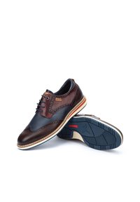 Chaussures brogue en cuir pour hommes avec un schéma de couleurs bleu marine et marron, perforations décoratives, lacets ronds et semelle en caoutchouc avec un motif de crampons.