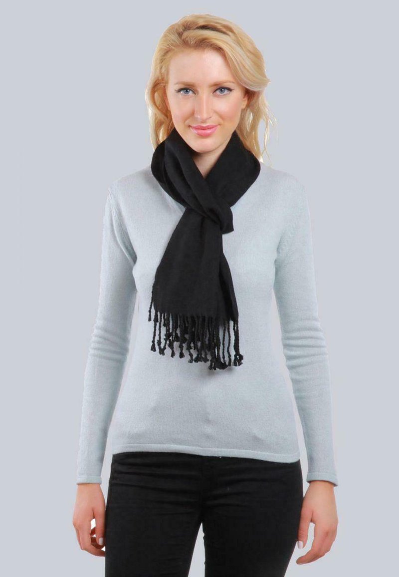 Écharpe noire avec des extrémités à franges, portée sur un pull bleu clair. L'écharpe est faite d'un matériau doux, tombant fluidement autour du cou.