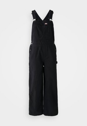 Zwarte denim dungarees met brede pijpen, verstelbare schouderbanden, een voorktas en zilveren hardware-accenten. Glad van textuur, minimaal ontwerp.