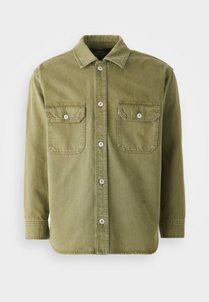 Oliven grøn skjorte med knapper lavet af blødt stof, der har to brystlommer med klapper, synlige knapper og en krave.