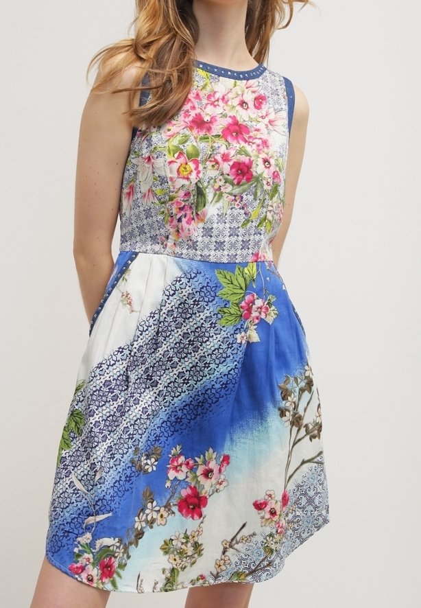 Robe sans manches avec un motif floral et des motifs en rose, bleu, vert et blanc, avec un corsage ajusté et une jupe évasée.