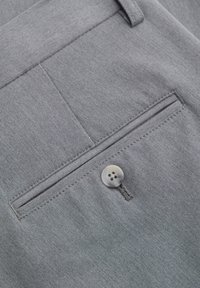 Harmaat kangashousut sileällä pinnalla, joissa on yksi takatasku, joka on varmistettu harmaalla napilla sekä hienovaraisia ompeleita.