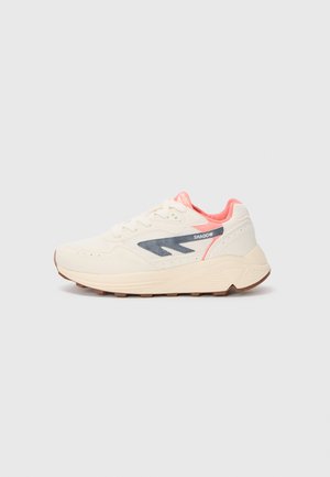 Zapatillas color crema con un upper texturizado, detalle del logo en azul marino, acentos rosas en la lengüeta y el talón, y una suela de goma.