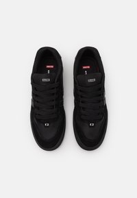 Zapatillas negras con una combinación de ante y malla, que presentan un diseño texturizado, perforaciones y cordones planos. Logo en la lengüeta.