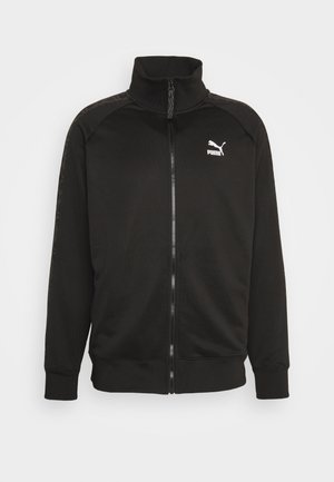 Čierna bunda na zips s vysokým golierom. Vyrobená z hladkej látky, obsahuje logo PUMA v bielej farbe a bočné panely s textúrovanými detailmi.
