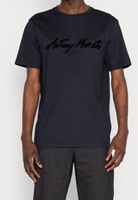Námořnická bavlněná tričko s krátkým rukávem, kulatým výstřihem a vyvýšeným černým nápisem "Antony Morato" přes hruď. Hladká textura a standardní střih.