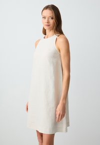 Ärmelloses, knielanges Kleid aus hellbeigem Leinen mit entspannter Passform. Hat einen runden Ausschnitt und einen leicht ausgestellten Saum. Einfaches Design.