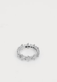 Sudraba gredzens ar zvaigžņu formas dizainu ap joslu. Gluda tekstūra ar spīdīgu apdari; iekšējā pusē iegravēts "MAPLE".