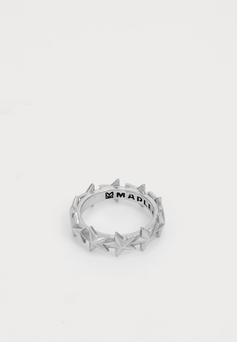 Sudraba gredzens ar zvaigžņu formas dizainu ap joslu. Gluda tekstūra ar spīdīgu apdari; iekšējā pusē iegravēts "MAPLE".
