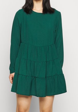 Robe longue à manches longues verte en tissu doux, présentant un design à volants superposés avec un col rond.