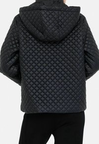 Chaqueta negra acolchada con capucha, con un patrón de rombos, mangas anchas y un ajuste relajado. Textura suave y brillante.