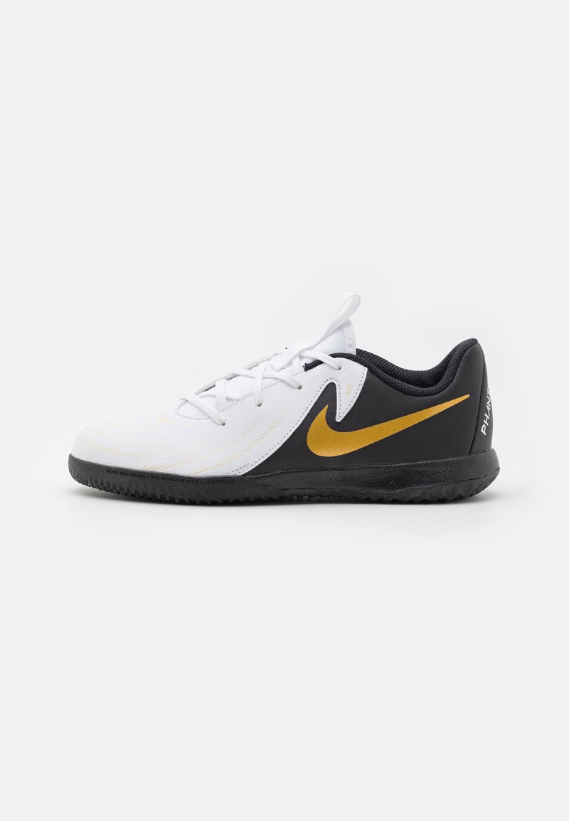 Witte en zwarte sportieve schoen met een gestructureerde bovenkant, gouden Nike-logo en rubberen zool. Beschikt over veters en details op de achterkant van de hiel.