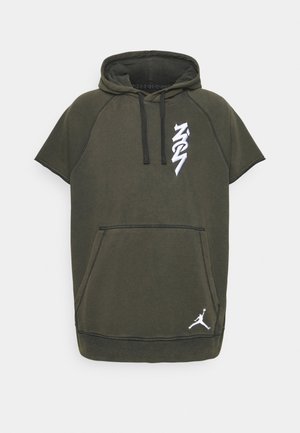 Donkergroene korte mouw hoodie met voorzak in kangaroestijl, zwarte trekkoorden, witte verticale tekst "NYC" en een wit Jumpman-logo vlak bij de zoom.