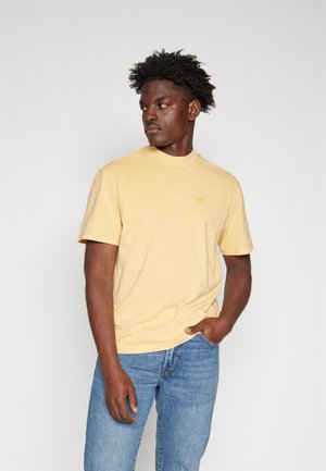 T-shirt di cotone gialla a maniche corte e collo rotondo, con un piccolo logo ricamato dello stesso colore sul petto.