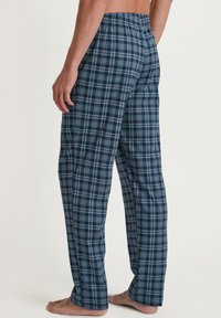 Gestreepte pyjamabroek in donkerblauw met een rood en lichtblauw geblokt patroon. Elastische tailleband, losse pasvorm, lichtgewicht stof, enkel lengte.