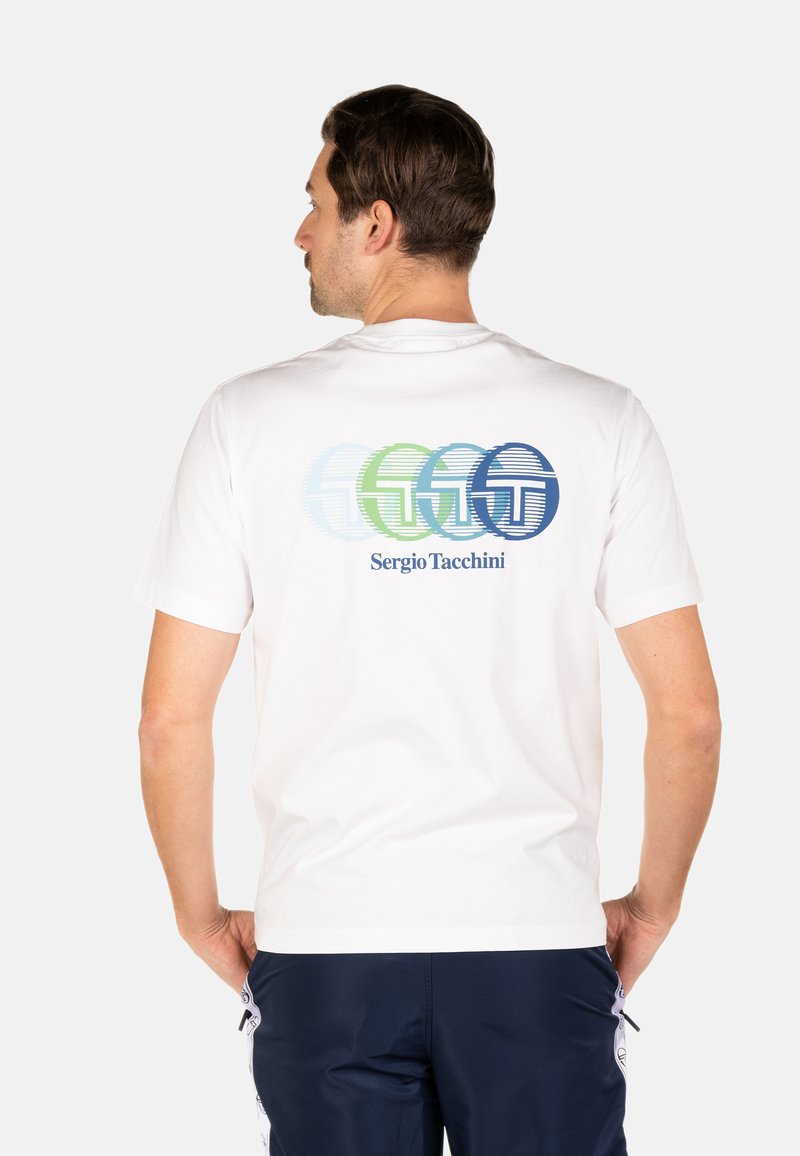 T-shirt en coton blanc présentant des graphiques de logos circulaires colorés au dos. Comprend le nom de la marque "Sergio Tacchini" en texte bleu.