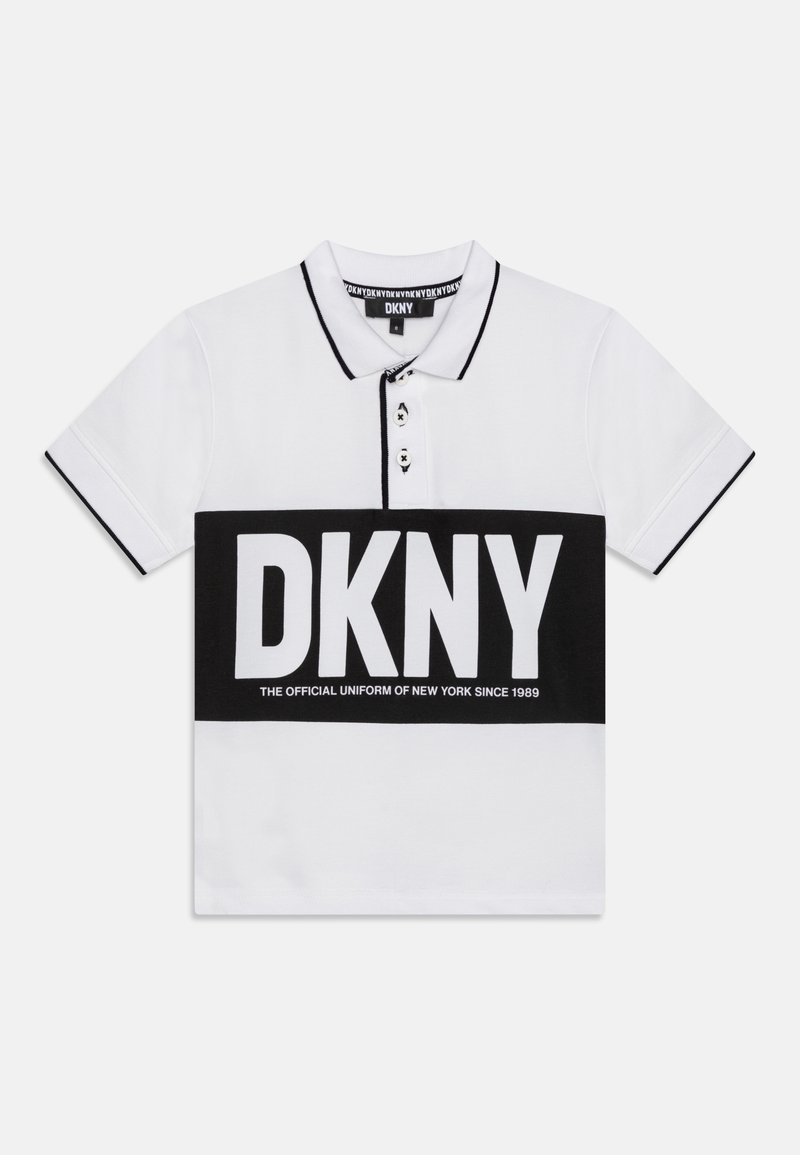 Polo blanc avec bordure noire au niveau du col et des manches, avec une bande horizontale noire comportant un grand texte blanc DKNY et un slogan plus petit en dessous.