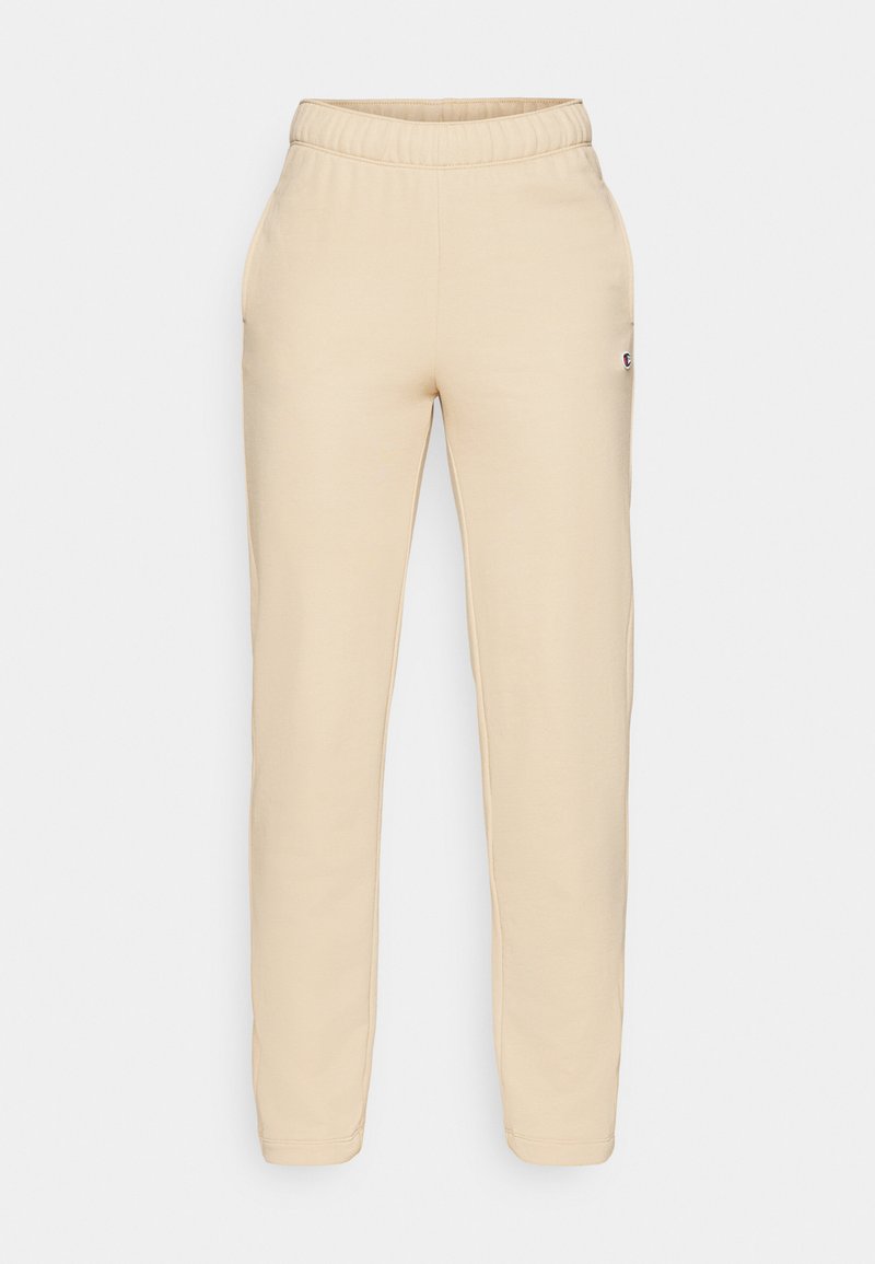 Pantalons de jogging en coton beige avec une taille élastique, des poches latérales et un petit logo cousu sur la jambe gauche. Texture lisse et coupe fuselée.