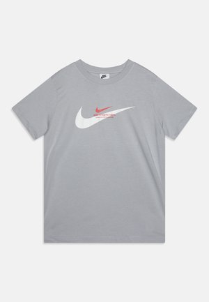 T-shirt en coton gris à manches courtes, arbore de grands graphismes du logo Nike en blanc et rouge sur le devant, dos uni et col rond.