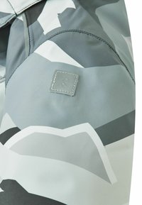 Kurtka we wzór kamuflażu w odcieniach szarości, wykonana z gładkiej, błyszczącej tkaniny, z małą naszywką z logo na ramieniu.