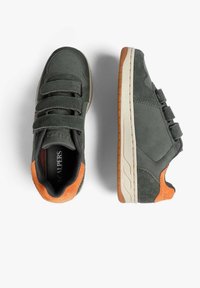 Zapatillas gris oscuro con tres correas de velcro, acentos naranjas en el talón, mediasoles blancos y suelas de goma marrón, mostradas desde vistas superior y lateral.