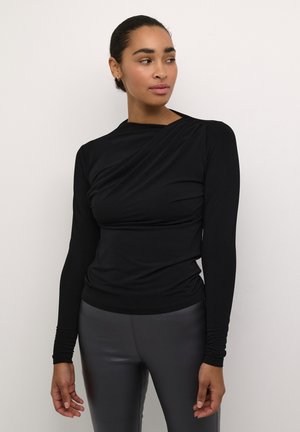 Top negru cu mânecă lungă și un design drapat. Construit dintr-un material elastic, are un gât rotund și o croială ajustată, asociat cu colanți gri.