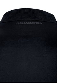 Polo nero con colletto testurizzato e logo "KARL LAGERFELD" opaco sul retro. Tessuto morbido con una finitura liscia.
