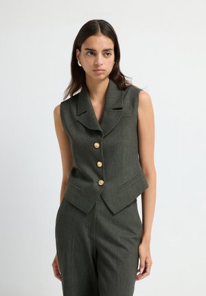 Sleeveless dark green vest with a notched collar, five gold buttons, and side pockets; tailored fit with a cropped design.