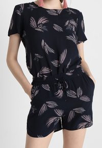 Navy playsuit with short sleeves and floral patterns in light pink. Features an elastic waistband and drawstring for adjustable fit.