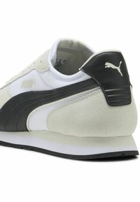 Białe sneakersy z czarnymi zamszowymi akcentami. Posiadają siateczkową cholewkę, zaokrąglony czubek i grubą gumową podeszwę. Logo po boku i na pięcie.