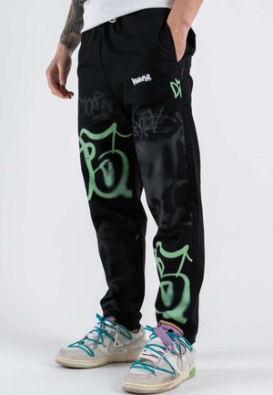 Pantaloni da jogging neri con grafiche verdi simili a graffiti e un logo bianco del marchio. Realizzati in tessuto morbido, con vita elastica e tasche.