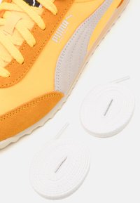 Puma Arizona tenisice u živopisnoj žutoj boji s sivim naglascima, s gornjim dijelom od teksturirane kože i tkanine; dolaze s dva bijela ravna vezica.