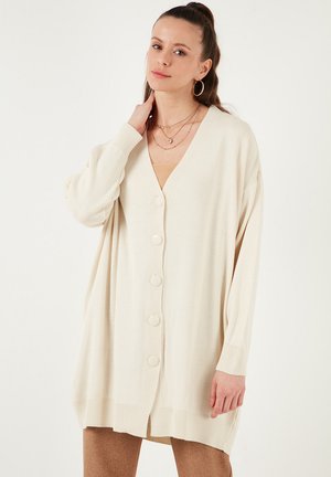 Cream-colored cardigan with a V-neck, long sleeves, and five front buttons. Soft knit texture, relaxed fit, and ribbed hem accents.