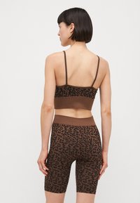 Smeđi leopard uzorak top s kratkim rukavima i odgovarajuće visoke šorts hlače, uski dizajn s podesivim naramenicama i teksturiranim materijalom.