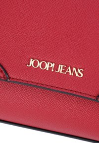 Borsa a tracolla in pelle rossa con texture, dotata di un logo dorato "JOOP! JEANS", con bordi neri e finitura liscia.