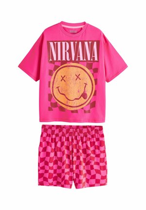 Svetlo roza kratka majica s kratkimi rokavi z napisom "NIRVANA" in grafiko nasmejanega obraza, v kombinaciji z roza šahovskimi elastikastimi kratkimi hlačami.