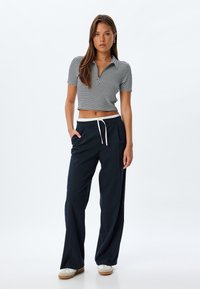 Randig navy och vit kortärmad polo med krage, kombinerad med löst sittande navybyxor med vit dragsko och fickor.