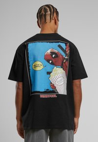 Black cotton t-shirt featuring a colorful Deadpool graphic on the back, depicting him holding popcorn with the text "HERE FOR THE COMMENTS."