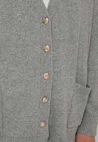Cardigan grigio a maglia con scollatura a V, dotato di sei bottoni dorati e una tasca anteriore. La trama è morbida e il design è a vestibilità comoda.