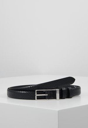 Ceinture en cuir noir texturé avec boucle rectangulaire argentée posée à plat sur une surface blanche.