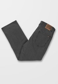 Jean en denim gris foncé plié avec une poche arrière et un patch de marque en cuir marron sur la ceinture, sur fond blanc.