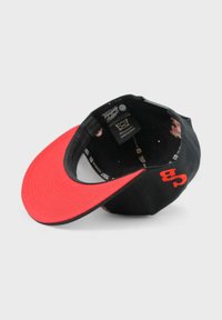 Musta baseball-hattu punaisella lippaalla ja kontrastivärisillä saumoilla. Sisältää sisävuoren kuosin, säädettävän hihnan ja brändilogon sisäpuolella.