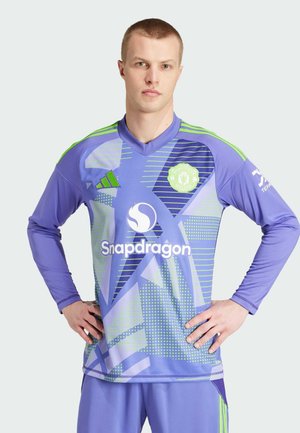 Lilanes langärmliges Fußballtrikot mit V-Ausschnitt, grünen Akzenten und verschiedenen geometrischen Mustern. Die Logos umfassen "Snapdragon" und das Vereinswappen.