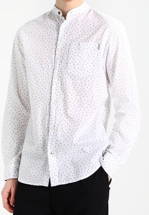 Camicia bianca a maniche lunghe con una piccola stampa a motivo. Presenta un colletto alla coreana e una tasca sul petto. Realizzata in tessuto leggero.