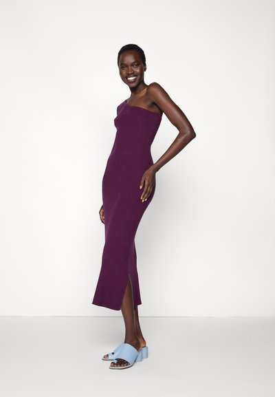 Vestido de malha sem mangas em roxo profundo com textura canelada e fenda lateral. Usado com sandálias slide azuis claras com salto bloco.
