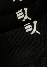 Schwarzer Strickstoff mit weißen, stilisierten japanischen Kanji-Zeichen, die in das Material eingewebt sind, im Detail nah gezeigt.