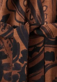 Tejido marrón con un patrón floral abstracto en negro, con un cinturón atado en la cintura y una textura suave.